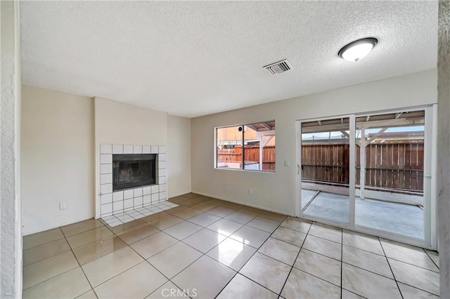 unfurnished living room featuring baseboard heating, a fireplace, a textured ceiling, and light tile patterned floors