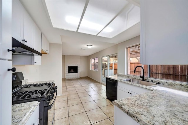 kitchen with light tile patterned flooring, sink, black appliances, a tile fireplace, and white cabinets