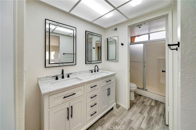 bathroom featuring a shower with door, vanity, hardwood / wood-style floors, and toilet