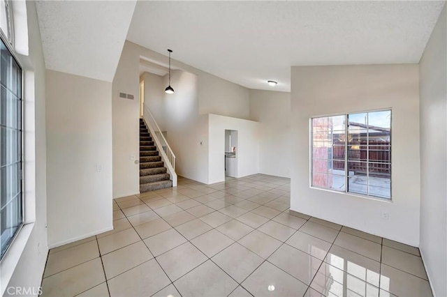 empty room with lofted ceiling and light tile patterned flooring