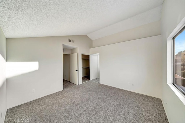 spare room featuring lofted ceiling, light colored carpet, and a textured ceiling