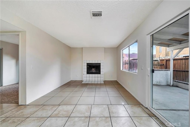 unfurnished living room featuring a fireplace, a textured ceiling, and light tile patterned floors