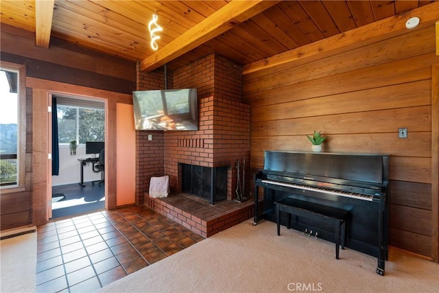 living room with wood ceiling, a brick fireplace, dark tile patterned flooring, and beam ceiling