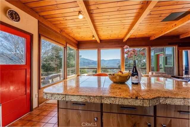 kitchen featuring a mountain view, beam ceiling, wooden ceiling, and light tile patterned floors