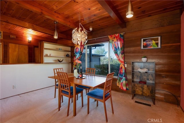 carpeted dining space with beamed ceiling, wooden walls, and wood ceiling