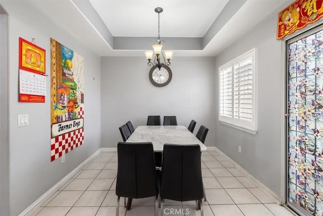 tiled dining area with an inviting chandelier and a tray ceiling