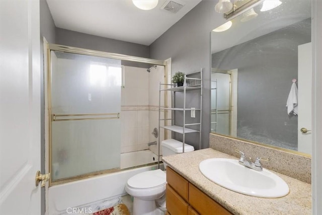 full bathroom with bath / shower combo with glass door, vanity, and toilet