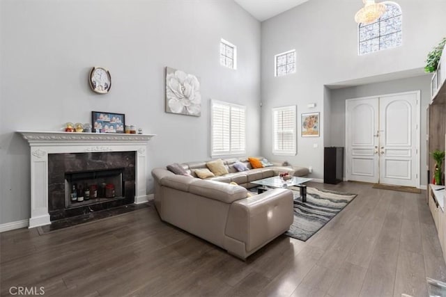 living room with a towering ceiling, a high end fireplace, and hardwood / wood-style floors