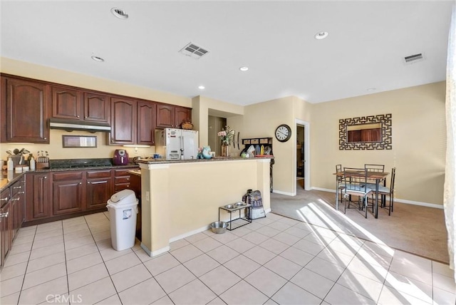 kitchen featuring black stovetop, light colored carpet, a kitchen island, and white fridge with ice dispenser