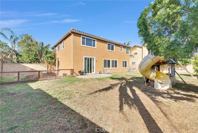 rear view of property featuring a playground and a lawn