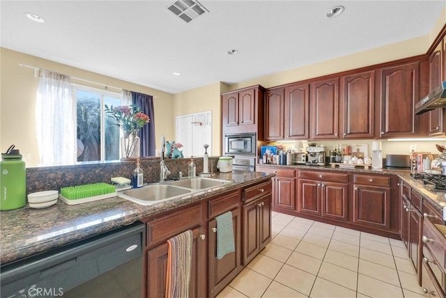 kitchen with stainless steel microwave, black dishwasher, sink, dark stone counters, and light tile patterned floors