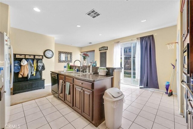 kitchen with dishwasher, sink, a center island with sink, and light tile patterned floors