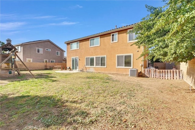 back of property featuring a playground, a yard, and central AC