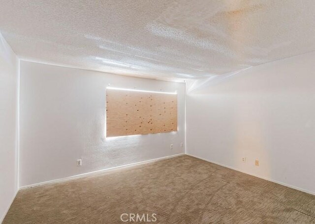 unfurnished room featuring carpet flooring and a textured ceiling