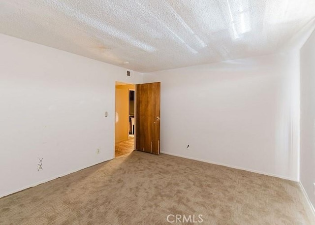 carpeted empty room featuring a textured ceiling