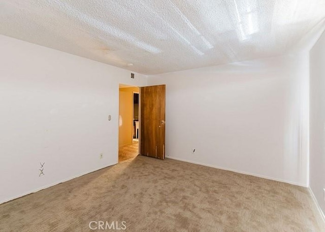 carpeted spare room featuring visible vents and a textured ceiling