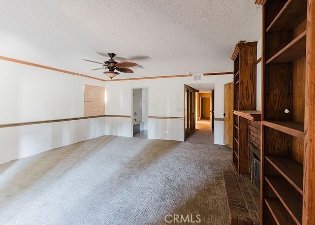 empty room with dark colored carpet, crown molding, ceiling fan, and a textured ceiling