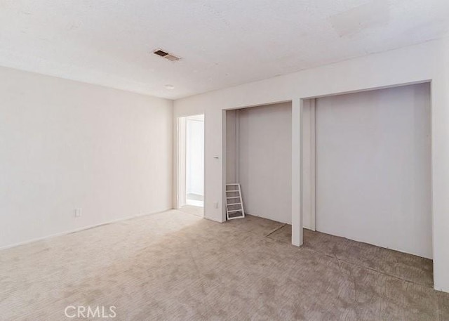 unfurnished bedroom featuring carpet floors and two closets