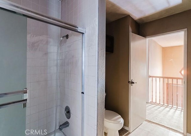 bathroom featuring combined bath / shower with glass door and toilet