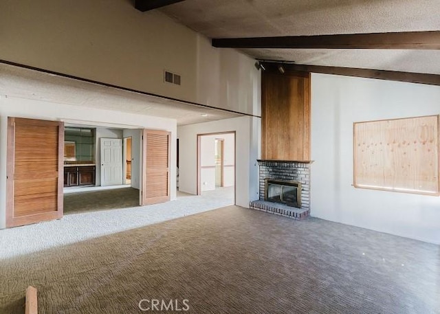 unfurnished living room with beam ceiling, visible vents, a fireplace, and carpet floors