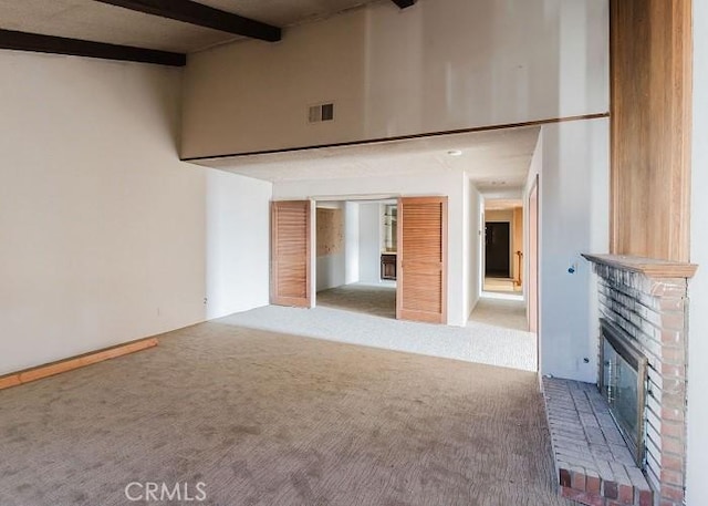 unfurnished living room with beamed ceiling, carpet floors, a brick fireplace, and a high ceiling