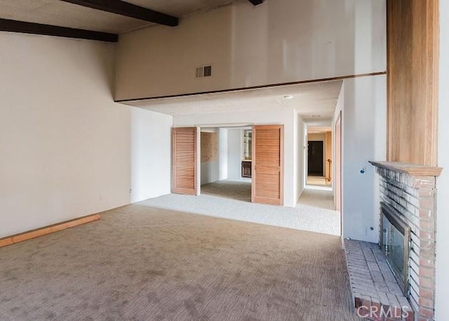 unfurnished living room with visible vents, carpet floors, beam ceiling, a high ceiling, and a fireplace