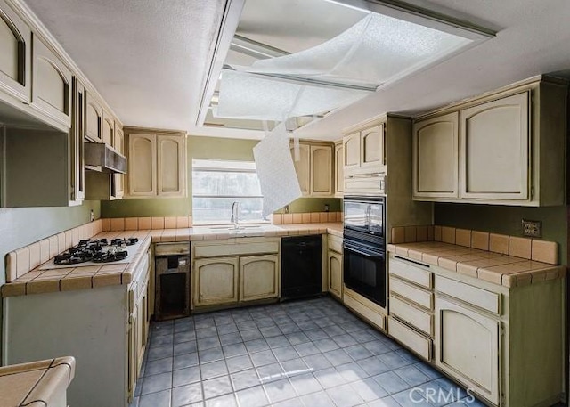 kitchen featuring sink, tile counters, light tile patterned floors, and black appliances