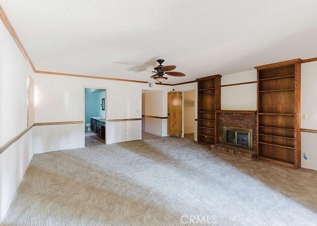 unfurnished living room featuring a brick fireplace, crown molding, carpet floors, and ceiling fan