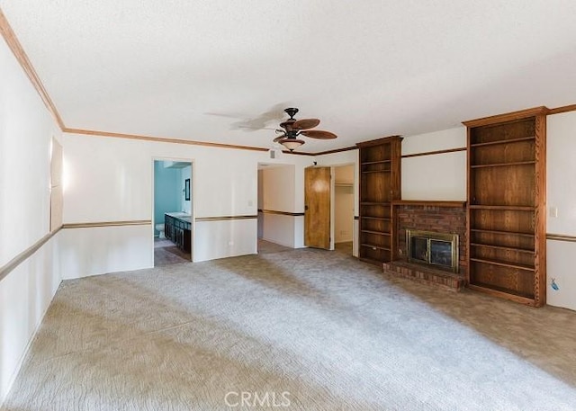 unfurnished living room with ornamental molding, a fireplace, ceiling fan, and carpet floors