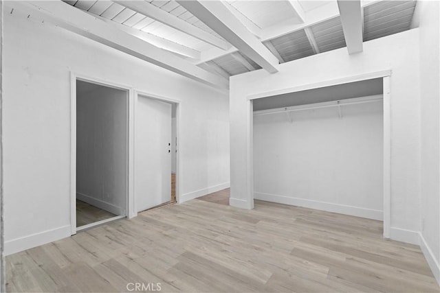 unfurnished bedroom featuring wood ceiling, light hardwood / wood-style floors, a closet, and lofted ceiling with beams