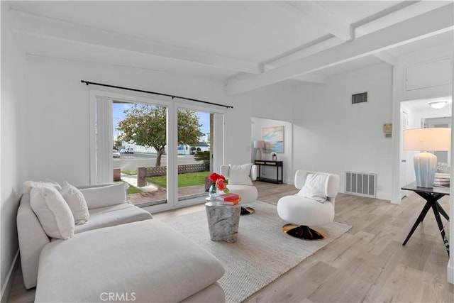 living room featuring lofted ceiling with beams and light hardwood / wood-style flooring