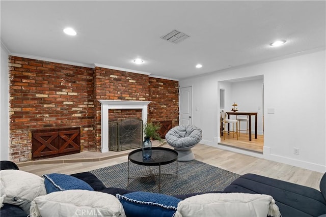 living room featuring a brick fireplace, ornamental molding, and light hardwood / wood-style floors