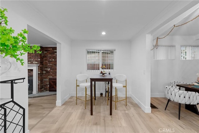 dining room with crown molding, a fireplace, and light wood-type flooring