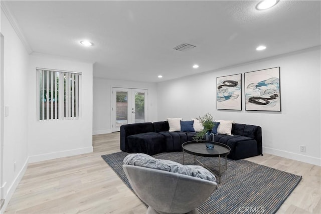 living room featuring french doors, ornamental molding, and light wood-type flooring