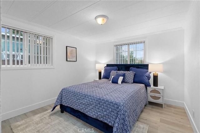 bedroom featuring ornamental molding and light wood-type flooring