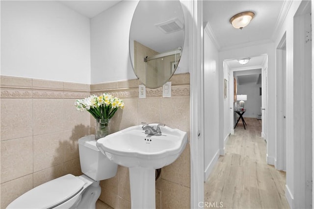 bathroom with ornamental molding, hardwood / wood-style floors, tile walls, and toilet