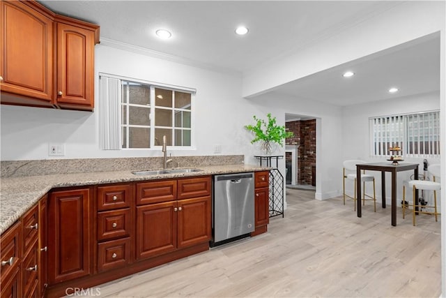 kitchen with sink, dishwasher, a fireplace, light stone countertops, and light hardwood / wood-style floors