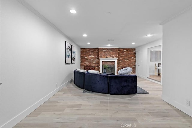 living room featuring crown molding, a brick fireplace, and light hardwood / wood-style flooring