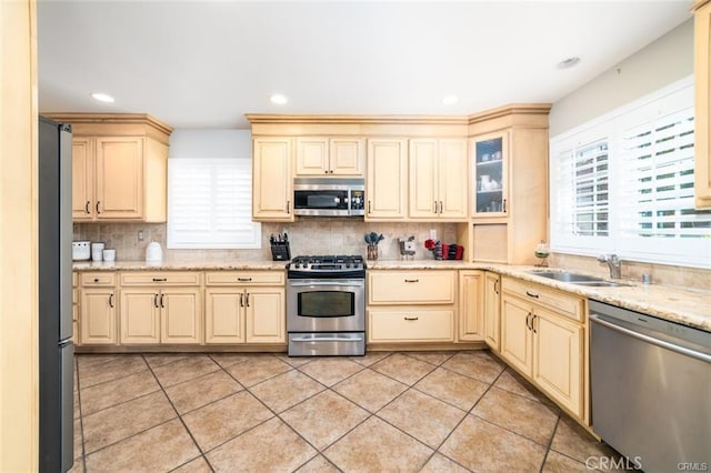 kitchen with sink, light tile patterned floors, backsplash, stainless steel appliances, and light stone counters