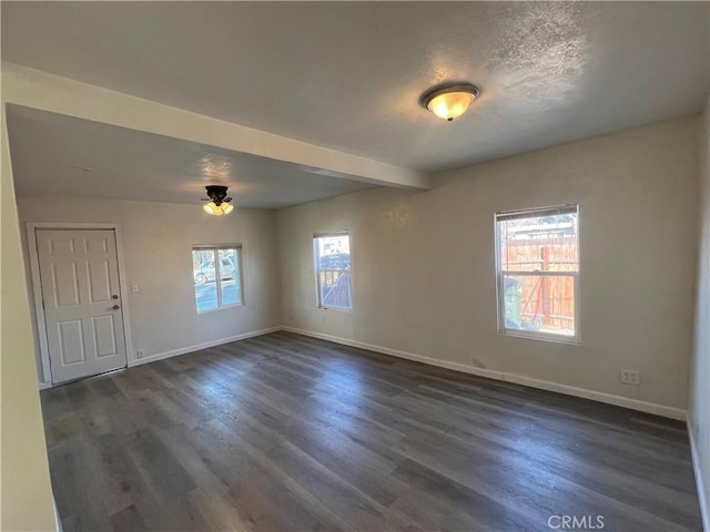 spare room featuring dark hardwood / wood-style floors, beam ceiling, and a textured ceiling