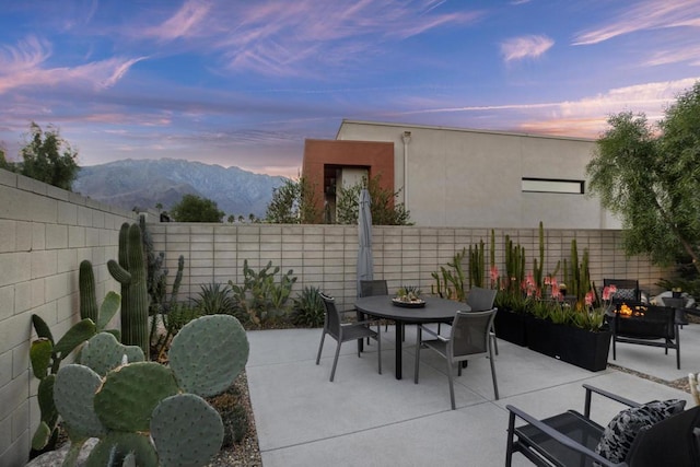 patio terrace at dusk featuring a mountain view and a fire pit