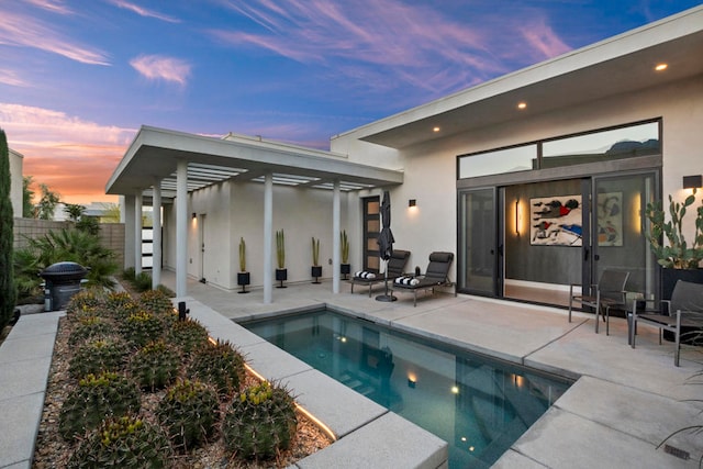 back house at dusk with a fenced in pool and a patio