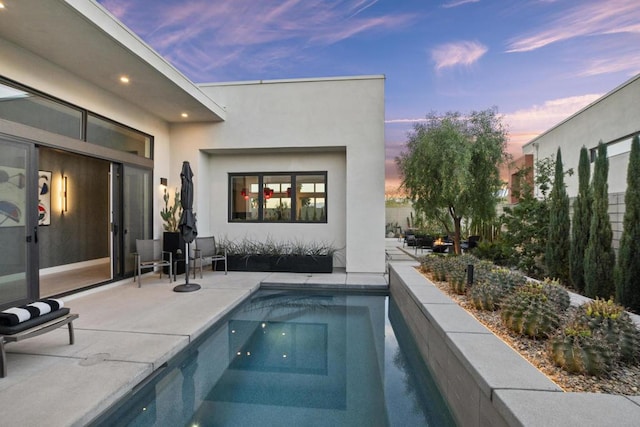 pool at dusk featuring a patio