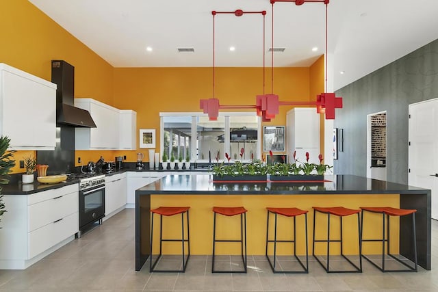 kitchen featuring white cabinets, a kitchen breakfast bar, wall chimney exhaust hood, and a kitchen island