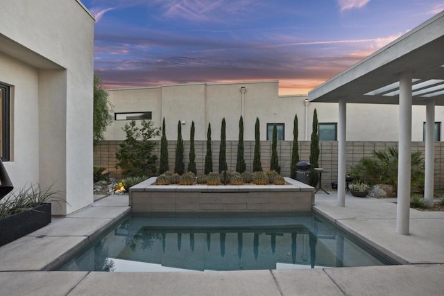 pool at dusk with a patio area