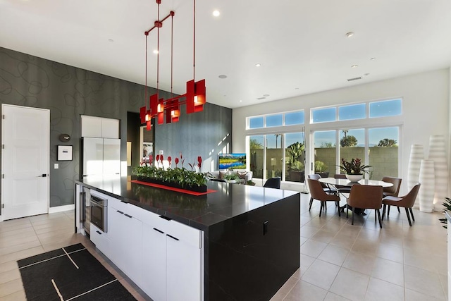 kitchen with white cabinetry, decorative light fixtures, stainless steel microwave, and a kitchen island