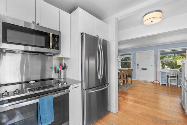 kitchen with appliances with stainless steel finishes, light wood-type flooring, and white cabinets