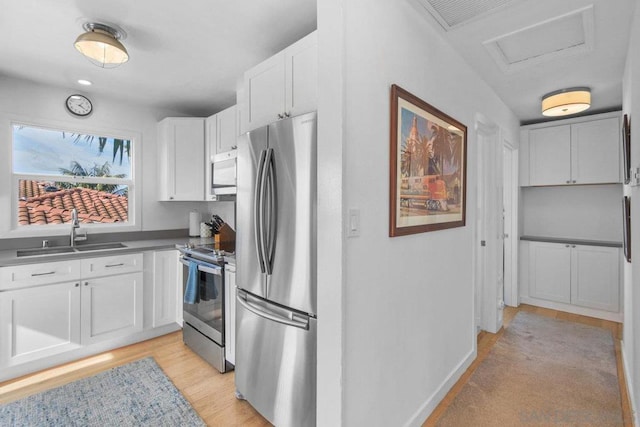 kitchen featuring appliances with stainless steel finishes, sink, light hardwood / wood-style flooring, and white cabinets