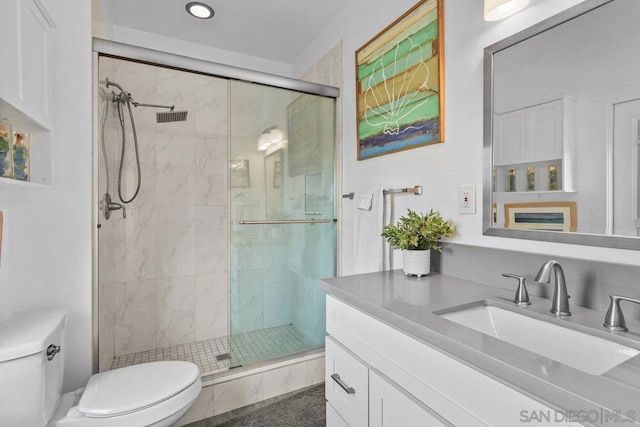 bathroom with toilet, vanity, and a shower with shower door