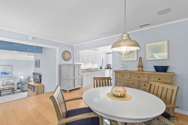 dining room with ornamental molding and light hardwood / wood-style flooring